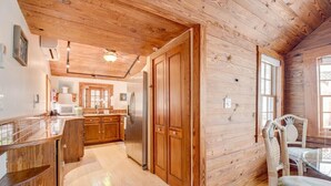 A wooden interior with a kitchen area, wooden cabinets, and a dining table with chairs. - Passover Cottage | Private Pool & Ideal Key West Location (Key West)