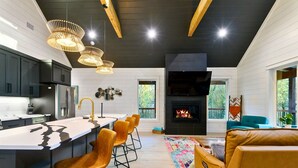 Eine moderne Küche mit Kochinsel, Barhocker und Kamin.