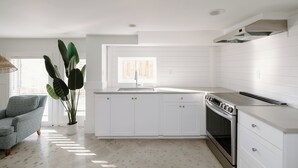 A modern kitchen with white cabinetry, a built-in oven, and a large window providing natural light.