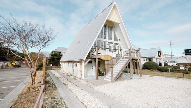 A triangular building with a balcony and a staircase leading to the entrance.
