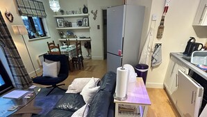 Un espace de vie compact comprenant un canapé, une table à manger, un coin cuisine et une petite table à manger avec des chaises.