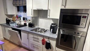 Une cuisine moderne avec des meubles blancs, un four encastré, un four à micro-ondes et une cuisinière.