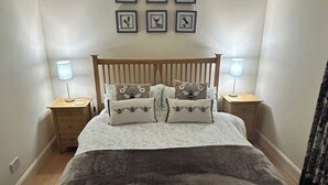 Une chambre à coucher comprenant un lit, deux tables de chevet, une tête de lit et six tableaux encadrés accrochés au mur.
