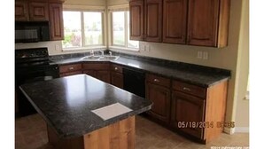 A kitchen with wooden cabinets, a granite countertop, and a built-in stove. - Spacious 5-bedroom house with WiFi, fitness room in wonderful Hooper (Hooper)