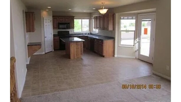 A spacious kitchen with wooden cabinets, a central island, and a large window providing natural light. - Spacious 5-bedroom house with WiFi, fitness room in wonderful Hooper (Hooper)