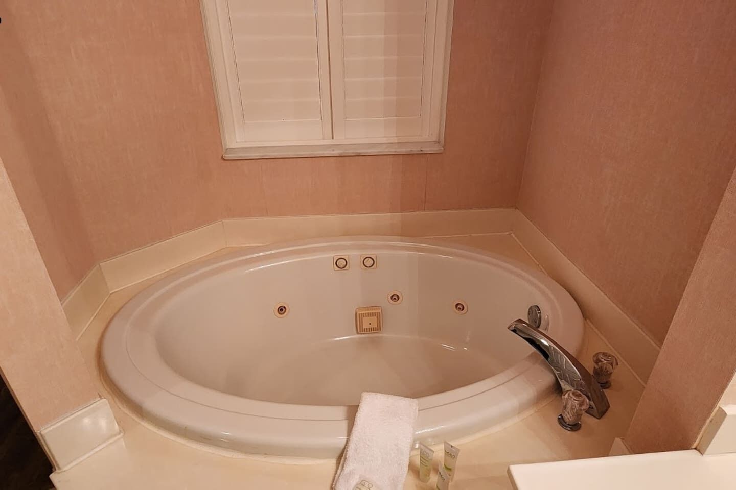 Un baño con bañera, ventana y perchero.
