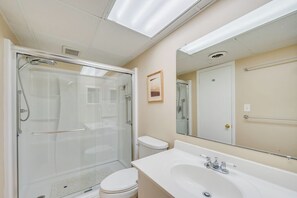 Une salle de bain moderne avec une douche à parois de verre, des toilettes, un lavabo et un grand miroir.