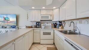 Une cuisine moderne avec des meubles blancs, un four à micro-ondes, une cuisinière et un lave-vaisselle.