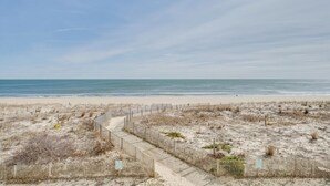 Une plage de sable bordée d’une clôture en bois, offrant une vue dégagée sur l’océan.