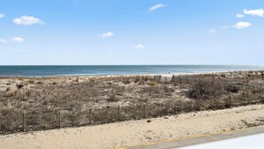 A beach with a sandy path and a wooden fence. - Stunning condo steps from the beach by Seaside Vacations & Sales (Ocean City)