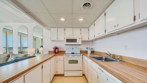 Una cocina compacta con armarios blancos, microondas, estufa y lavavajillas.