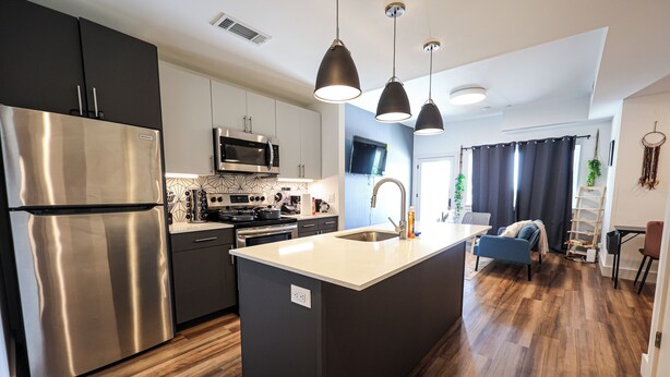 A modern kitchen with stainless steel appliances, a central island, and pendant lighting. - Studio Apartment - in*the*Philadelphia. (Philadelphia)