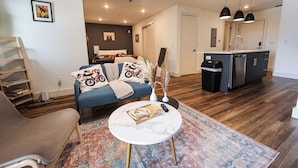 A modern living room with a sofa, coffee table, and a kitchen area with a sink and cabinets. - Studio Apartment - in*the*Philadelphia. (Philadelphia)