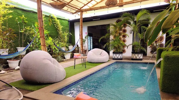 A pool area with a hot tub, two bean bags, and a hammock.
