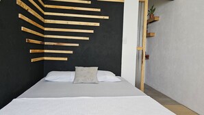 A bedroom with a bed, a black wall with wooden slats, and a small plant on a shelf.