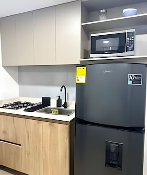 A kitchen with a stainless steel refrigerator, a microwave, and a gas stove. - 81 Living (Medellín)