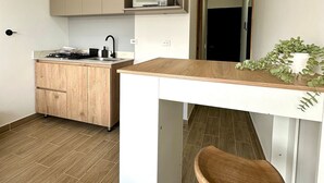 Een moderne keuken met houten kastjes, een magnetron en een klein kookeiland met een kruk.