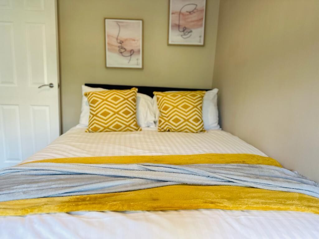Una cama con almohadas estampadas y una manta a rayas.