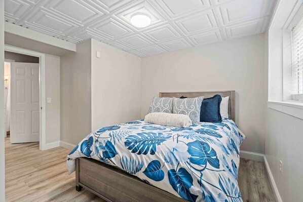 Un dormitorio con cama, cabecera de madera y ventana con persianas.