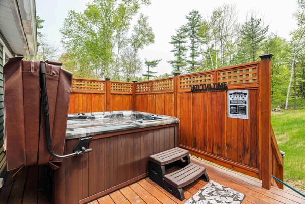 A hot tub with a wooden deck, a wooden fence, and a sign indicating 'HOT TUB TIME'.