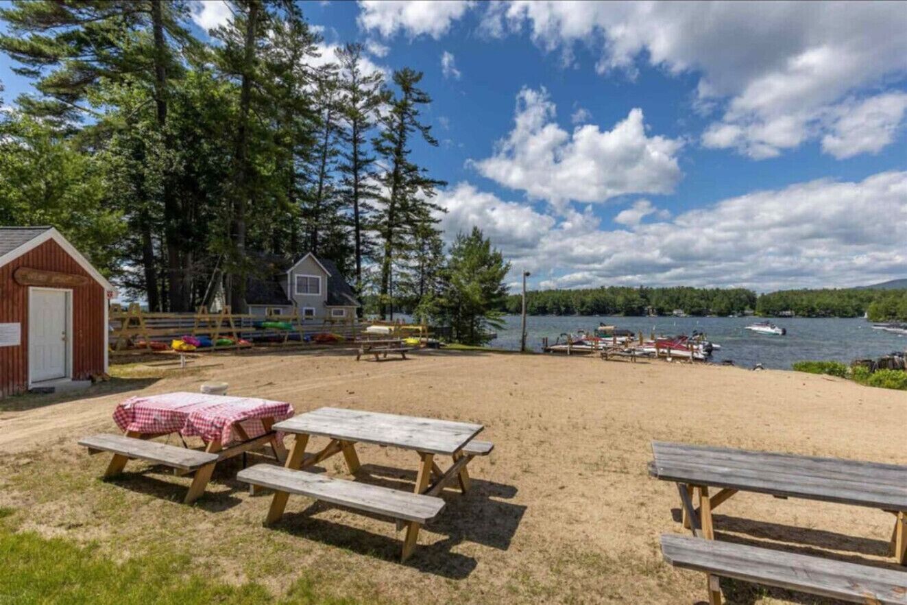 A beach area with picnic tables and a small cabin.