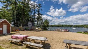 A beach area with picnic tables and a small cabin.