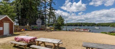 A beach area with picnic tables and a small cabin.
