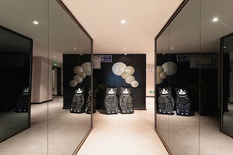 A hallway with mirrored walls, decorative wall art, and a reception desk.. Boru Hotel