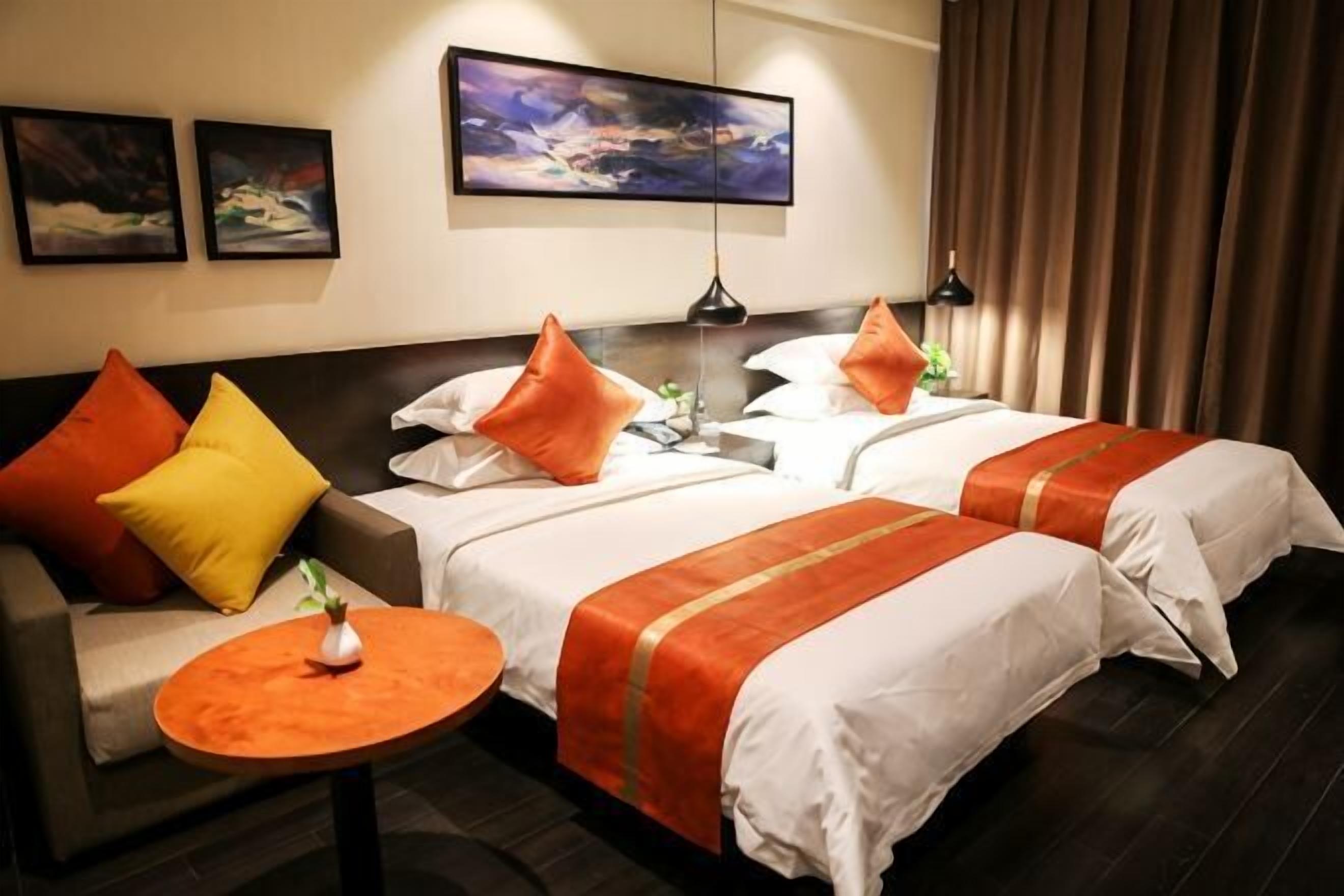 A hotel room with two beds, a sofa, a small round table, and a painting on the wall.. Boru Hotel