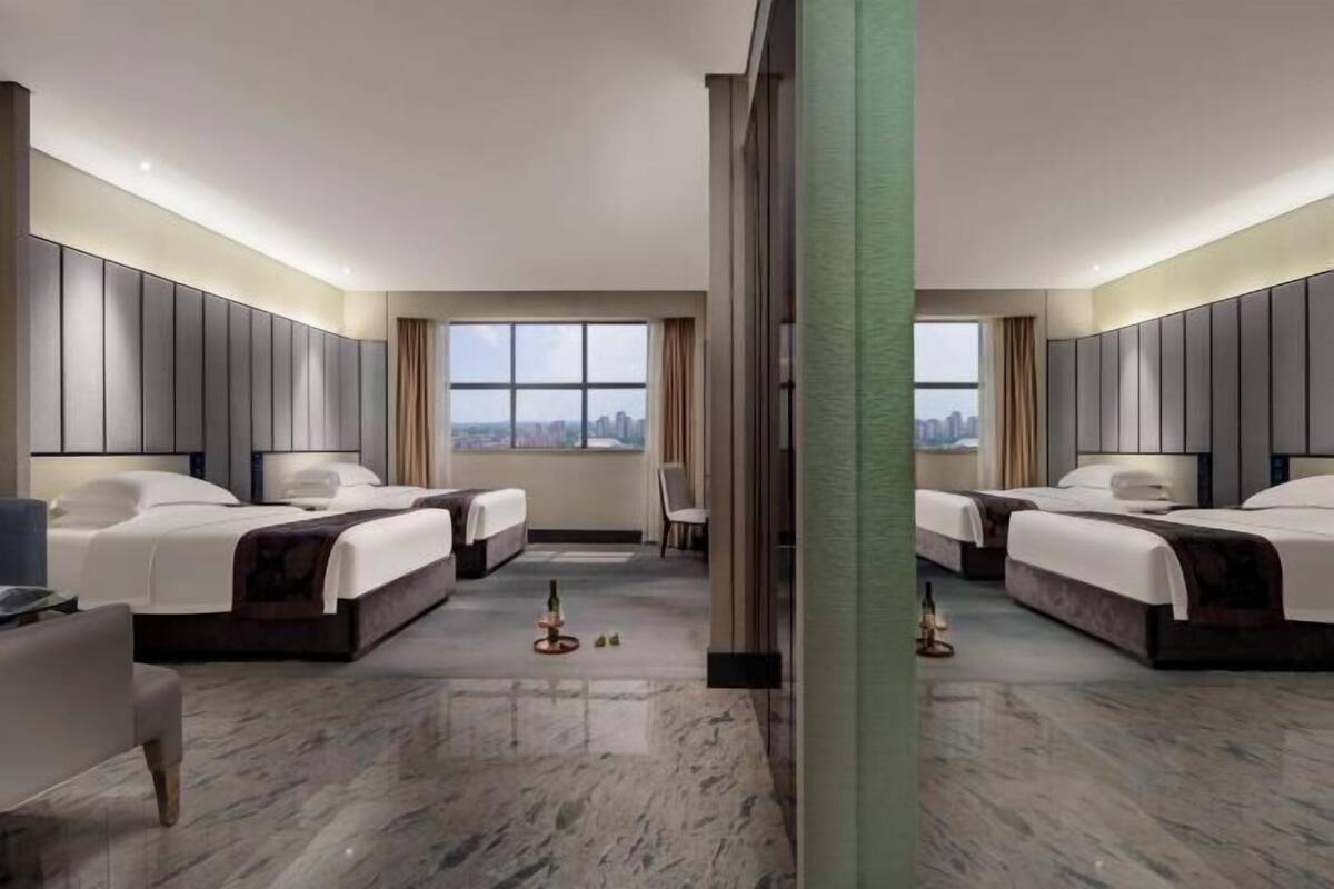 A hotel room with two beds, a large window, a city view, and a marble floor.
