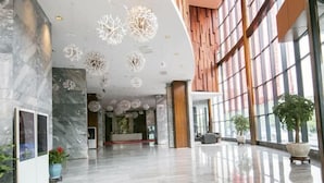 Un vestíbulo espacioso con suelo de mármol, ventanas amplias y candelabros modernos.