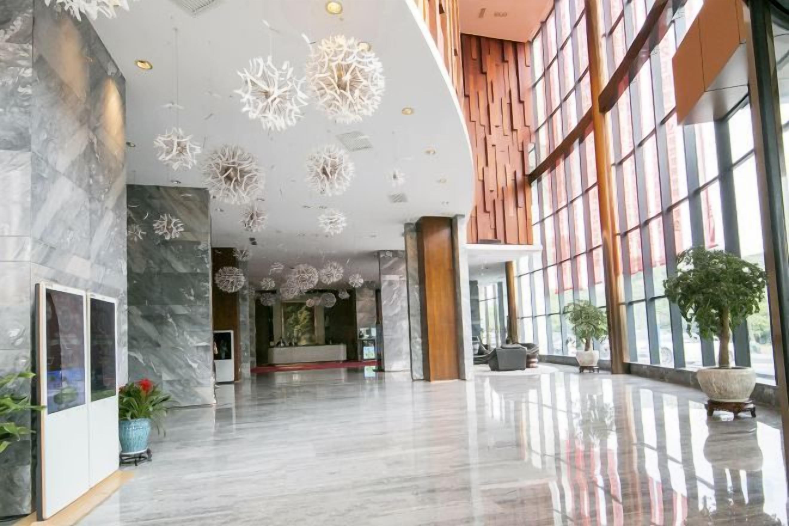 Un vestíbulo amplio con piso de mármol pulido, una mesa de recepción y ventanas grandes.