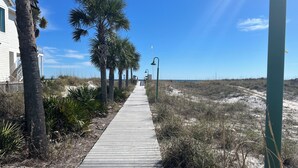 A wooden boardwalk lined with palm trees leading to a beach. - Charming 2-bedroom condo with WiFi, AC in lovely Destin (Destin)
