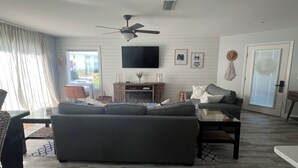 A living room with a sofa, a coffee table, a TV, and a ceiling fan. - Charming 2-bedroom condo with WiFi, AC in lovely Destin (Destin)
