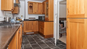 A modern kitchen with wooden cabinets, a microwave, and a gas stove. - 2 New Mill Cottages (Newton Abbot)