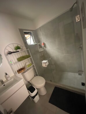 Une salle de bain moderne Ă©quipĂ©e de toilettes, dâun lavabo et dâune douche.