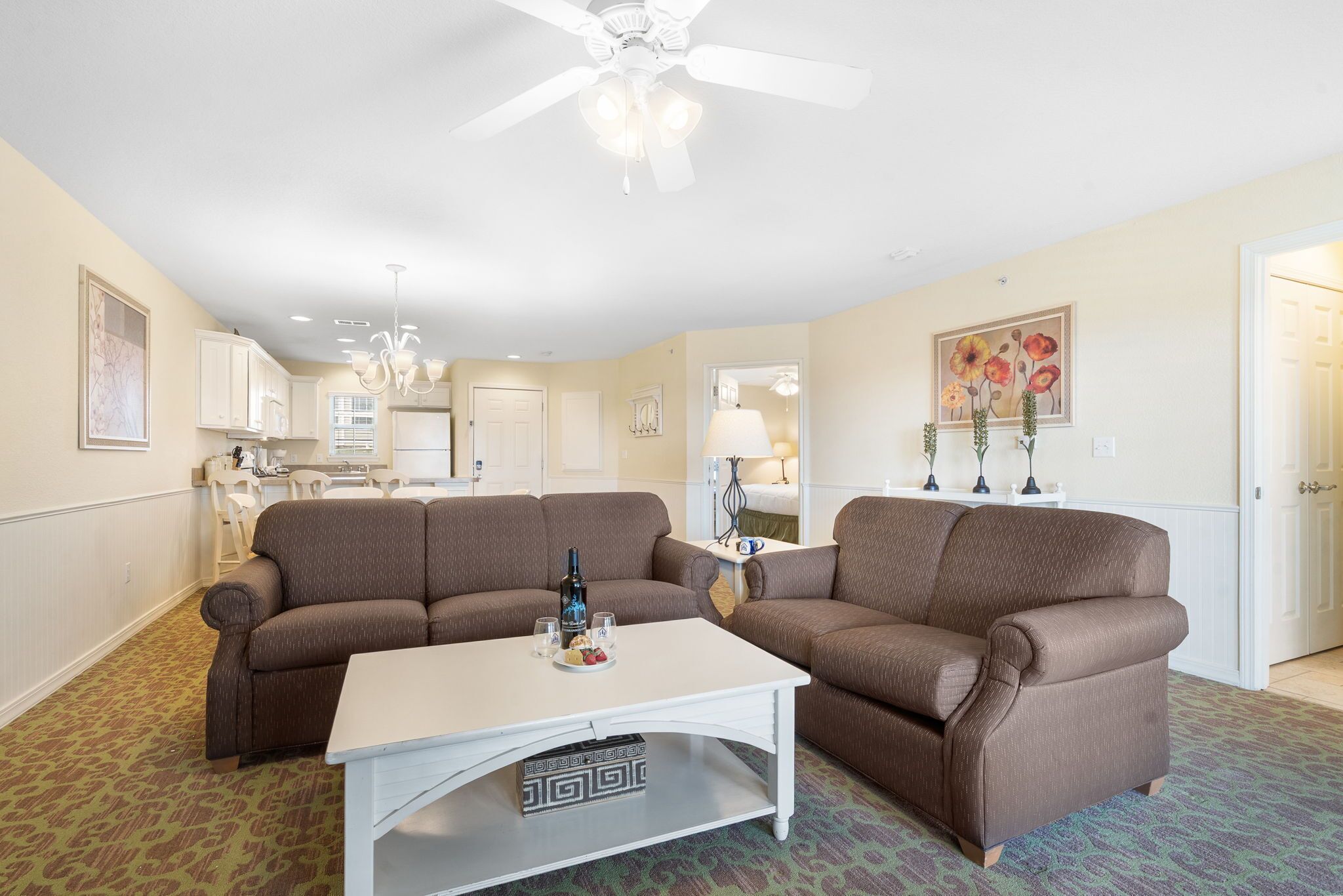 Ein Wohnzimmer mit zwei braunen Sofas, einem weißen Couchtisch und einem Deckenventilator.