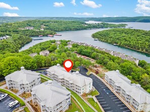 A multi-story hotel with a central courtyard, surrounded by lush greenery and a lake.