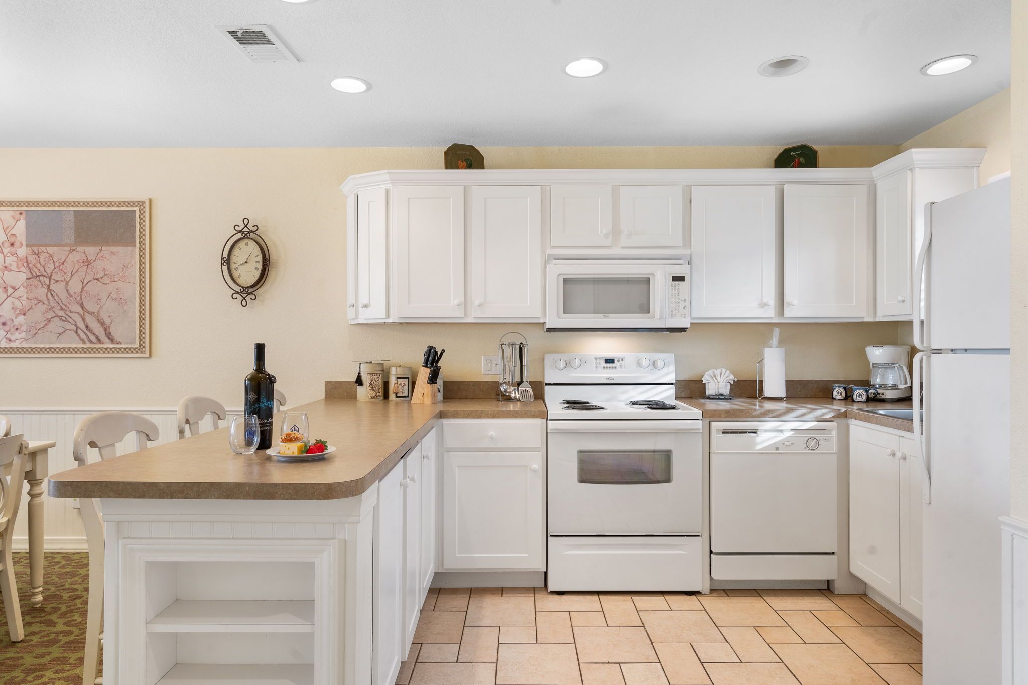 A modern kitchen with white cabinetry, a microwave, an oven, and a refrigerator.