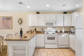 Una cocina moderna con armarios blancos, un microondas, un horno y un refrigerador.