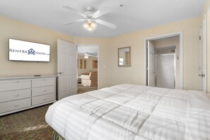 Ein Schlafzimmer mit einem großen Bett, einem Deckenventilator, einem Schminktisch und einem Fernseher, der 'RENTBRNSON.COM' zeigt.