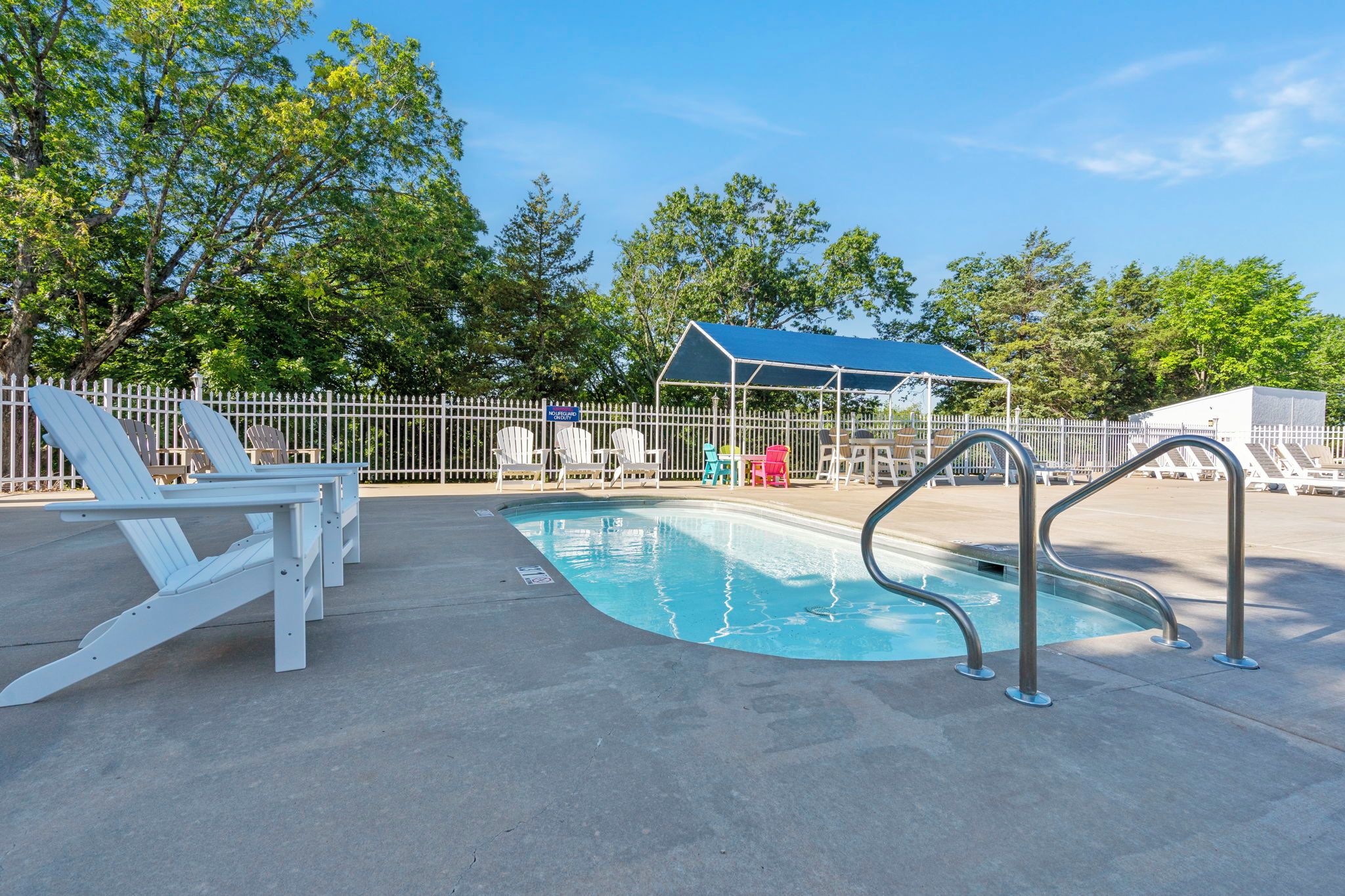 A pool area with lounge chairs, a covered seating area, and a fenced deck.