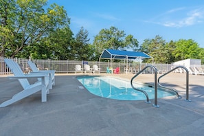 A pool area with lounge chairs, a covered seating area, and a fenced deck.