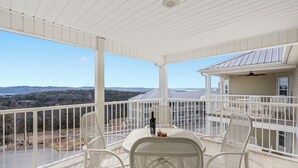 A covered outdoor seating area with a table and chairs, overlooking a residential neighborhood and distant hills. - Table Rock Lake-Access Kim City Condo w/ Community Pool, Mini Golf & Free Daily Tickets (Kimberling City)
