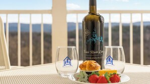 A bottle of wine, two glasses, and a plate with strawberries and a pastry on a balcony with a mountain view. - Table Rock Lake-Access Kim City Condo w/ Community Pool, Mini Golf & Free Daily Tickets (Kimberling City)