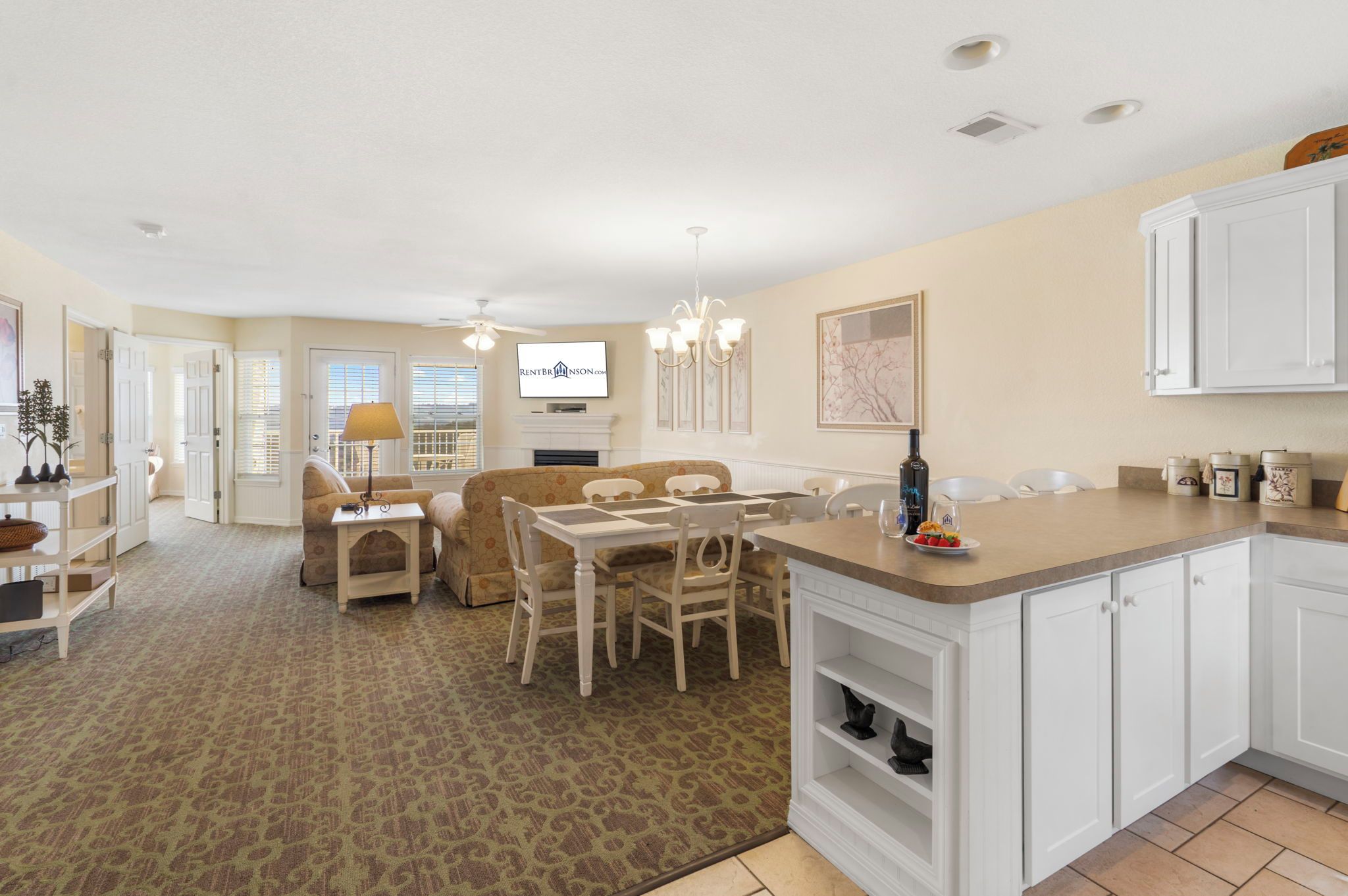 A spacious living area with a dining table, sofas, and a kitchen with white cabinetry.