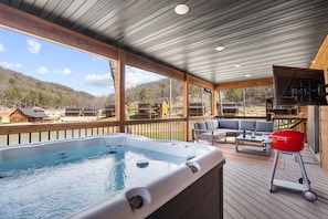 A hot tub on a wooden deck with a view of houses in the background.