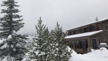 A snow-covered landscape with a building featuring large windows and a sloped roof.