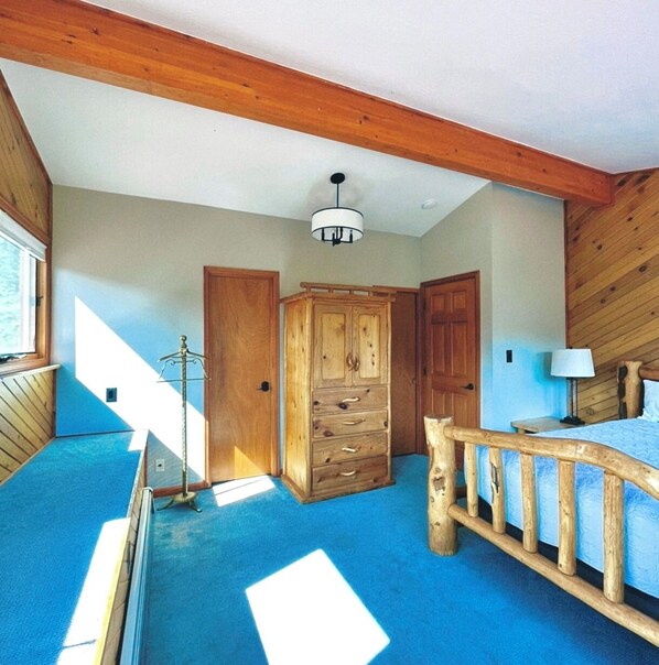 Une chambre à coucher avec un lit en bois, une armoire et un ventilateur de plafond.