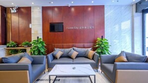 A modern lobby with a wooden accent wall, a flat-screen TV, and two sofas with cushions. - Derun Hotel Apartment (Guangzhou)